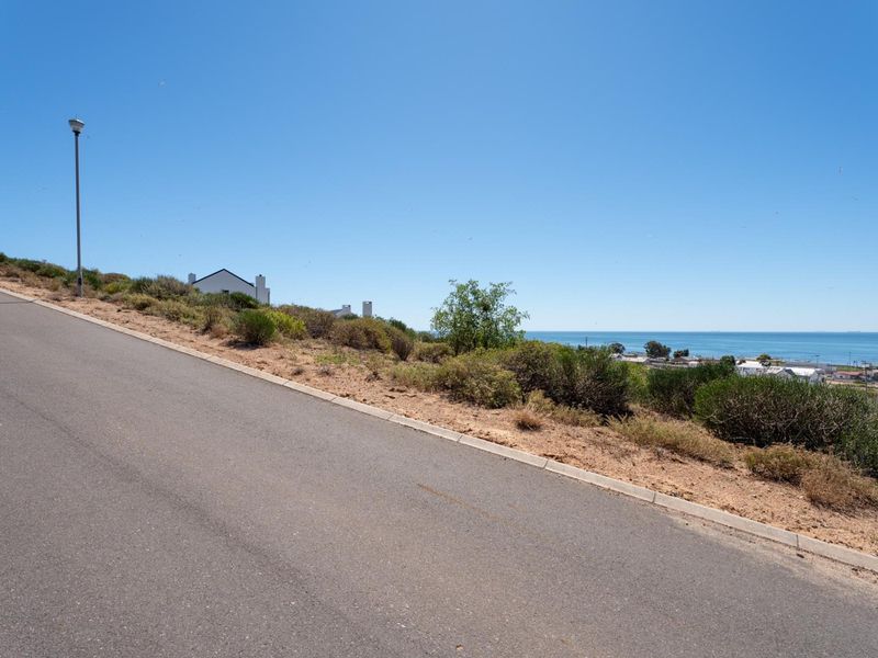 A view of the paved street and curbing adjacent to the vacant residential land, featuring coastal views in the distance.