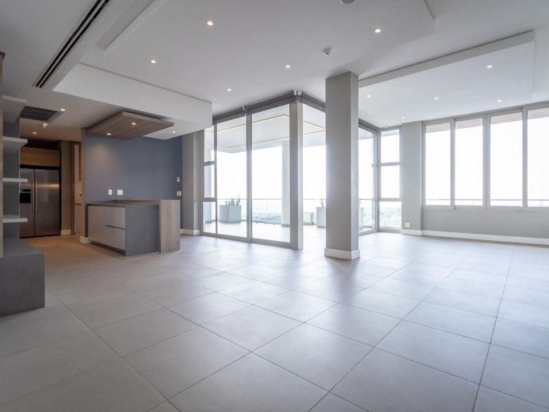 Spacious open-plan living area featuring modern tiled floors, recessed lighting, built-in cabinetry, and large sliding glass doors leading to a balcony.