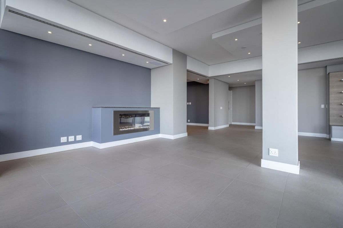 Spacious, modern open-plan living area featuring neutral grey tones, tiled flooring, recessed ceiling lighting, and a sleek built-in fireplace.