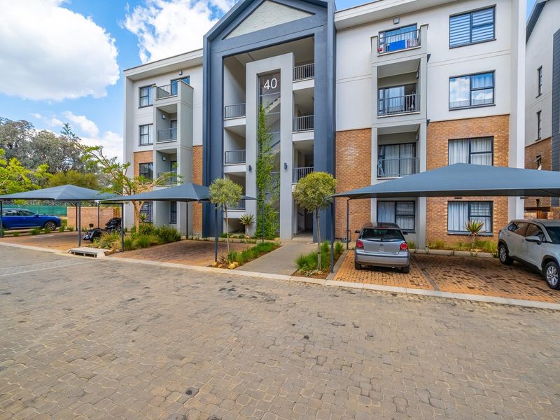 Front elevation of a modern apartment complex featuring brick and render finishes, covered parking bays, and private balconies.