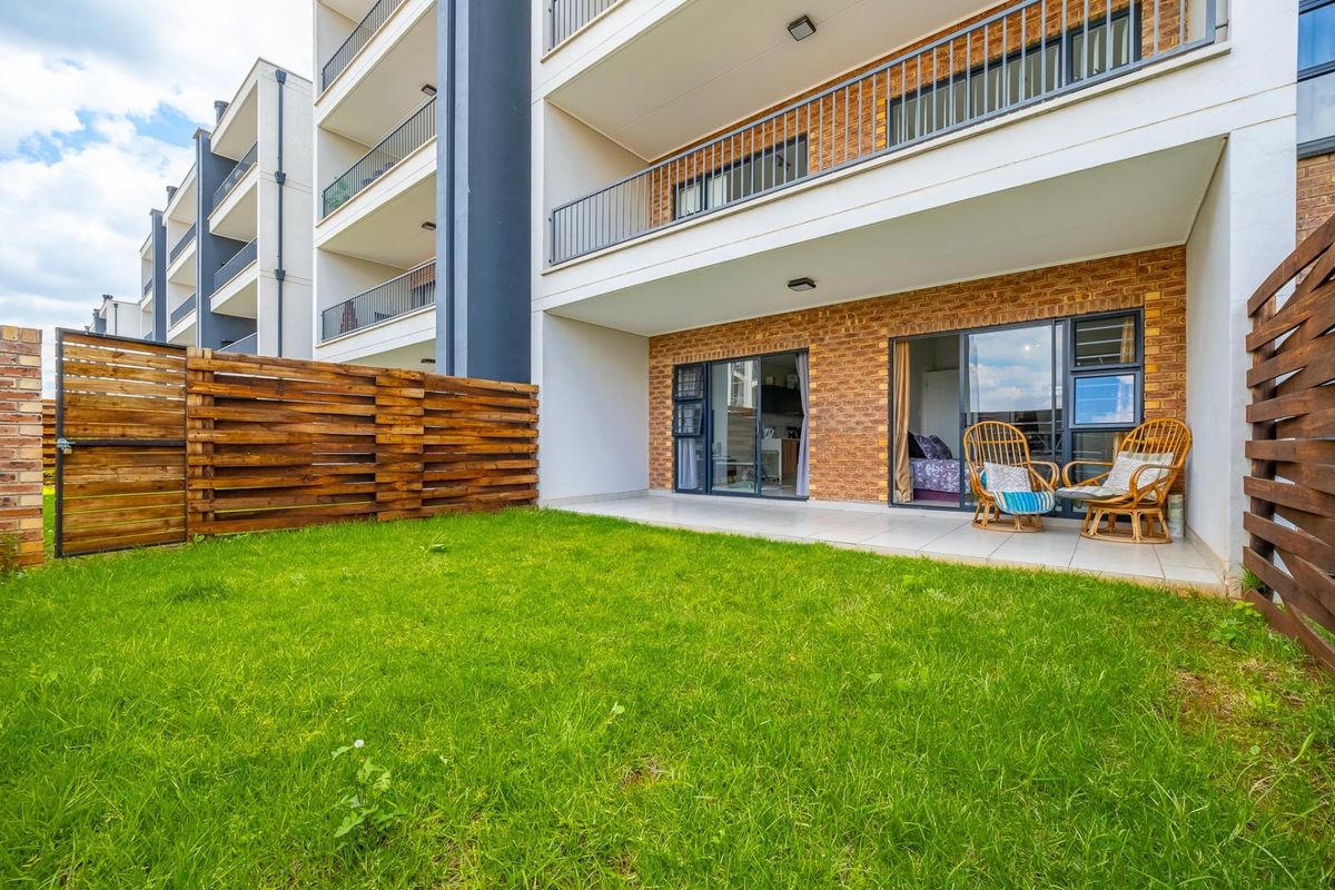 Ground floor apartment featuring a private tiled patio, brick exterior finish, and a small enclosed garden area with wooden fencing.