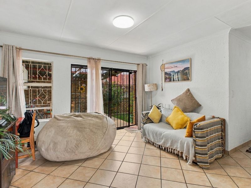 A living room featuring ceramic floor tiles, a sliding glass door with security gate, and direct access to the outdoor area.