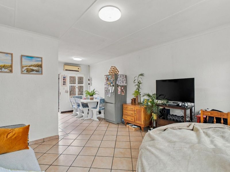 Open-plan living and dining area featuring tiled flooring and a wall-mounted air conditioning unit.