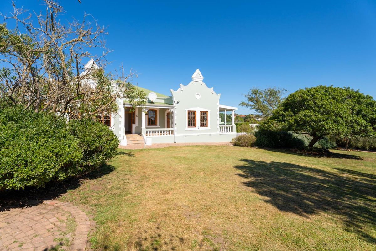 A well-maintained Cape Dutch style home featuring a classic gable, covered veranda, and expansive garden area.