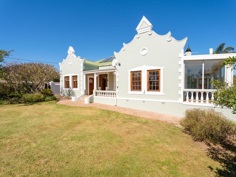 A well-maintained Cape Dutch style home featuring a covered patio, timber sash windows, and a spacious garden area.