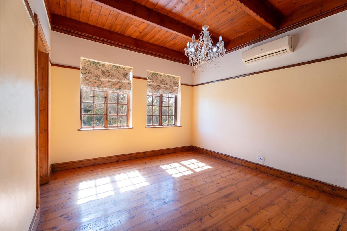 Spacious bedroom featuring warm timber flooring, a vaulted timber ceiling, and a wall-mounted air conditioning unit.