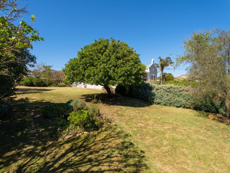 A spacious, well-maintained garden featuring mature trees, lush lawn, and established shrubbery, providing a serene outdoor setting.