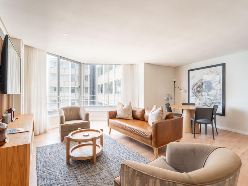 A bright and modern living area featuring timber flooring, large floor-to-ceiling windows, and elegant timber wall paneling, creating a warm and inviting atmosphere.