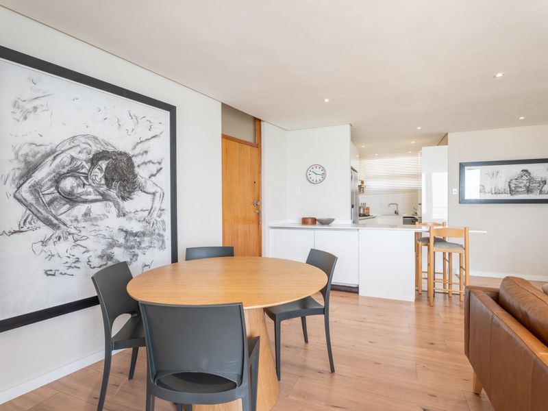 An open-plan living and dining area featuring modern laminate flooring, recessed lighting, and a functional kitchen with a central island.