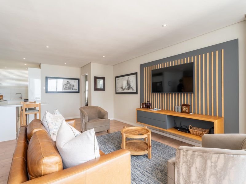 Modern open-plan living area featuring a stylish timber slat feature wall with integrated media console, recessed lighting, and seamless flow into the kitchen.