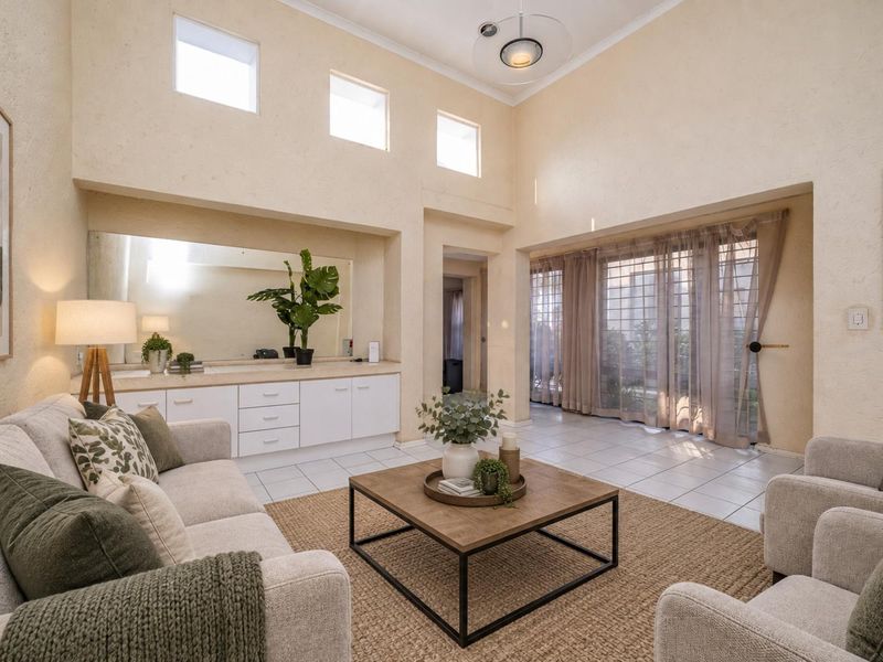 Spacious living room featuring high ceilings, clerestory windows, tiled flooring, and built-in cabinetry with a large integrated mirror.