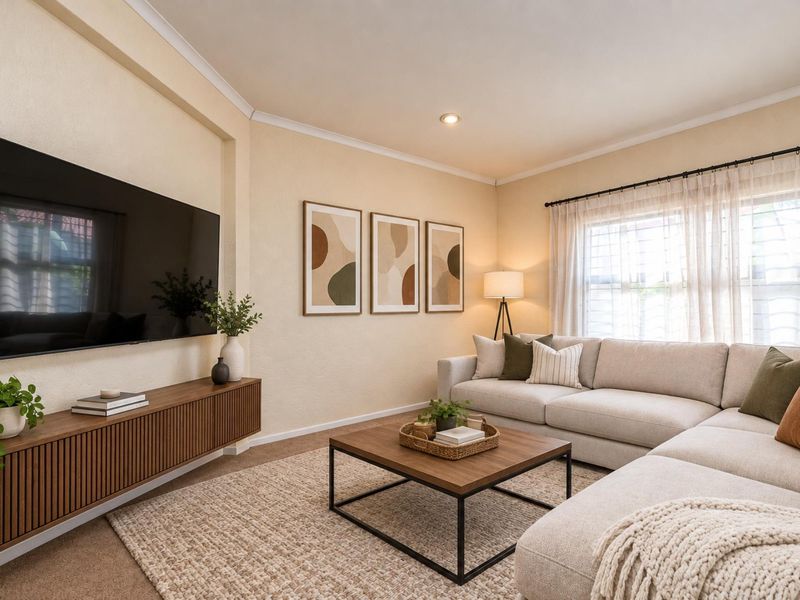 A well-maintained living room featuring neutral wall tones, recessed lighting, and a custom wall-mounted media console.