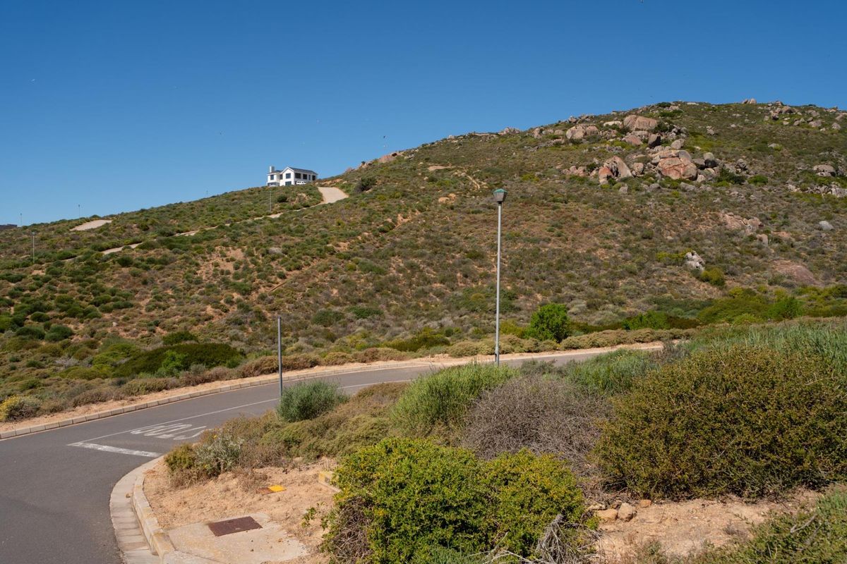 A view of the paved street and surrounding natural landscape, showing the access road leading up the hillside.