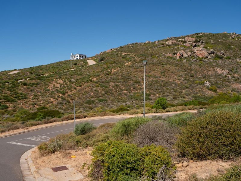 A view of the paved street and surrounding natural landscape, showing the access road leading up the hillside.