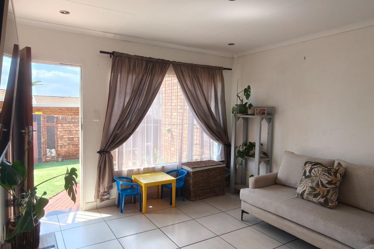 A bright living room featuring tiled flooring, recessed lighting, and direct access to the rear garden through a sliding door.