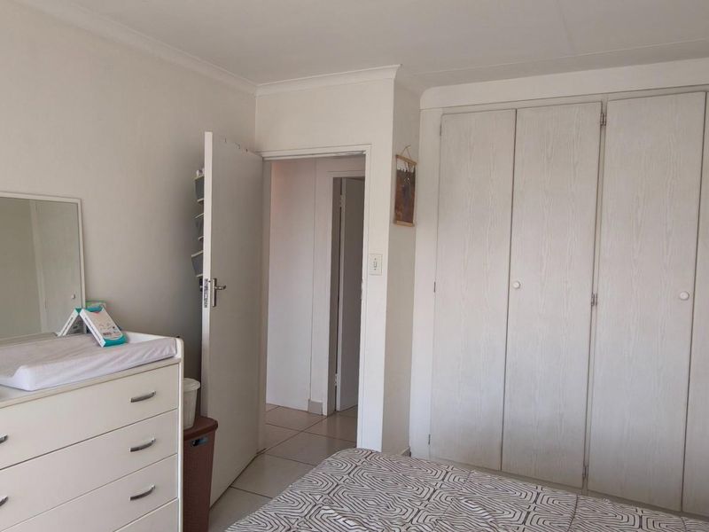 A bedroom featuring built-in cupboards, tiled flooring, and coving, providing a functional and neutral space.
