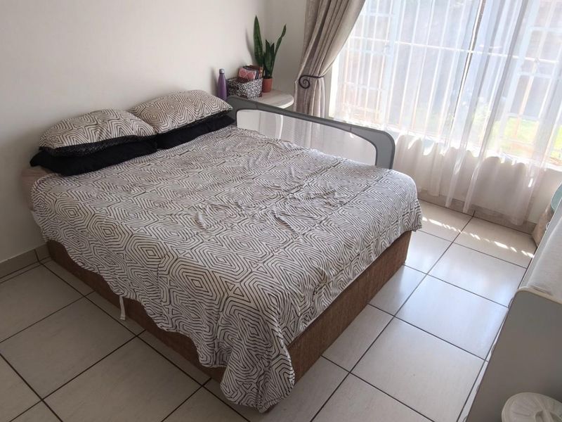 A functional bedroom featuring tiled flooring and large windows with curtain rails, providing natural light and a neutral foundation for personalization.