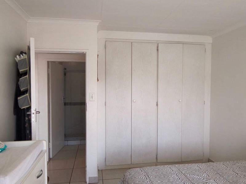 A bedroom featuring built-in cupboards and direct access to an en-suite bathroom, finished with neutral walls and coving.