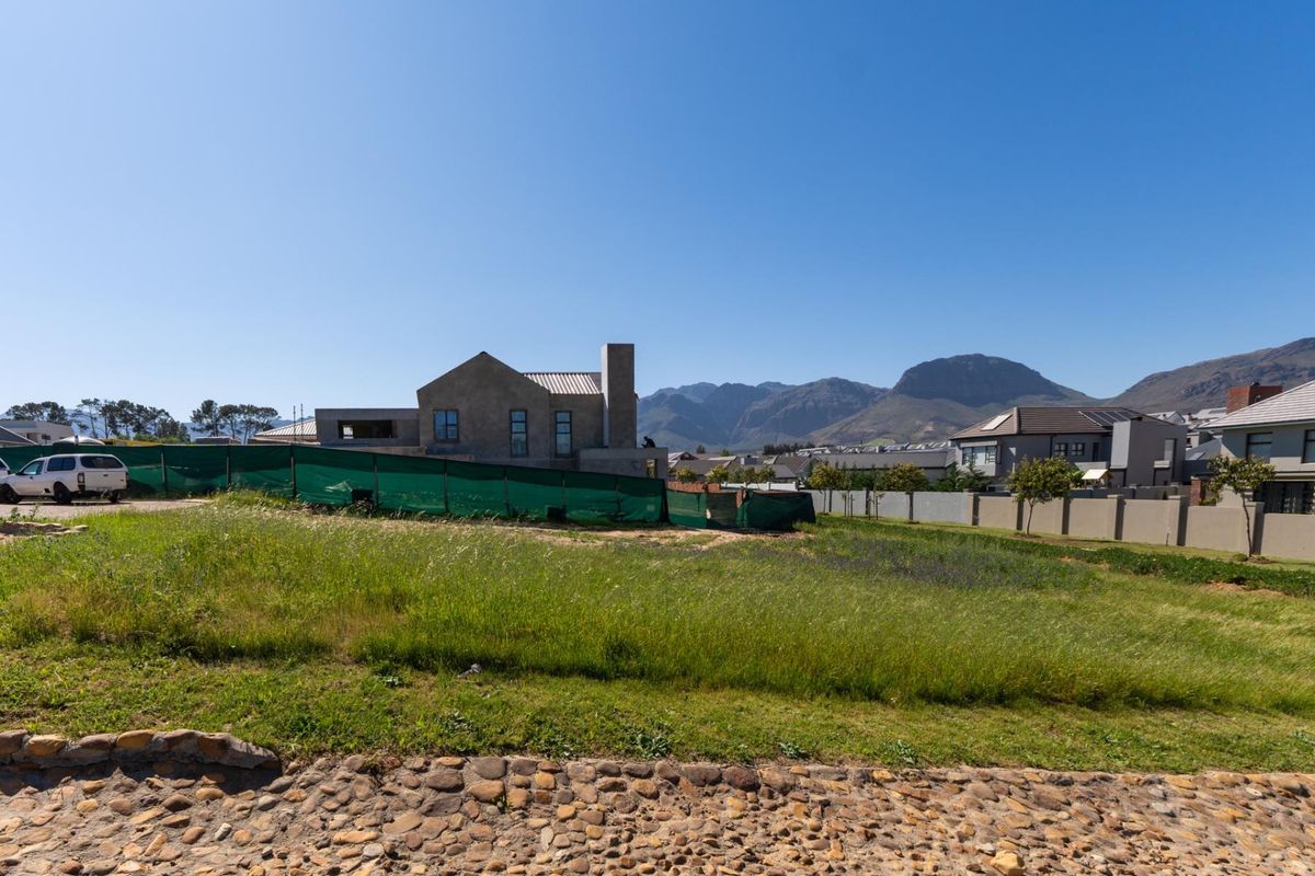 A view of a vacant residential plot with surrounding perimeter fencing and mountain views in the background.