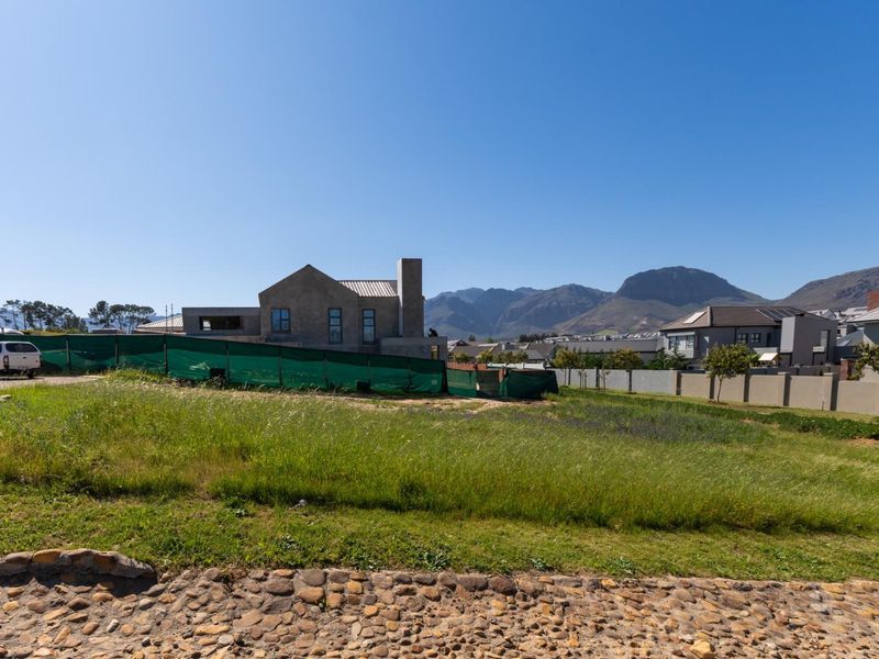 A view of a vacant residential plot with surrounding perimeter fencing and mountain views in the background.