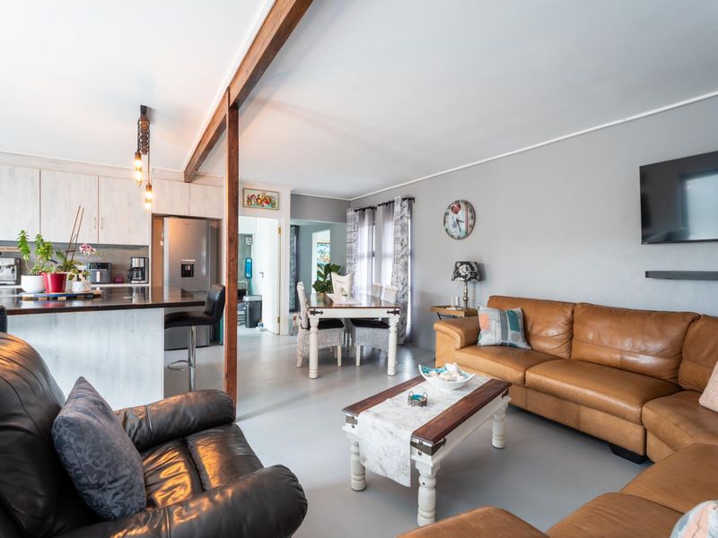 An open-plan living and kitchen area featuring a central island, exposed timber beam, and neutral finishes, creating a spacious and functional layout.