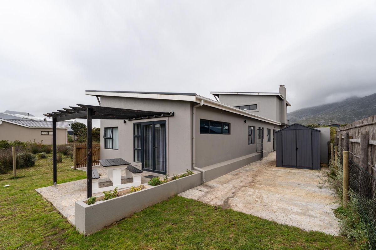 Rear view of the property featuring a paved patio area with a pergola, a detached storage shed, and a low-maintenance garden.