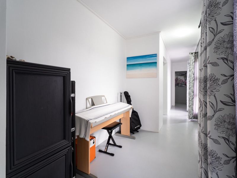 A bright, neutral-toned hallway featuring smooth flooring and clean white walls, providing a clear transition between living spaces.