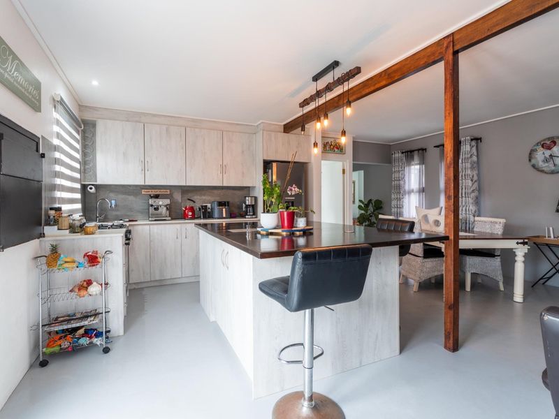 Open plan kitchen and dining area featuring a central island, modern cabinetry, and a rustic timber support beam.