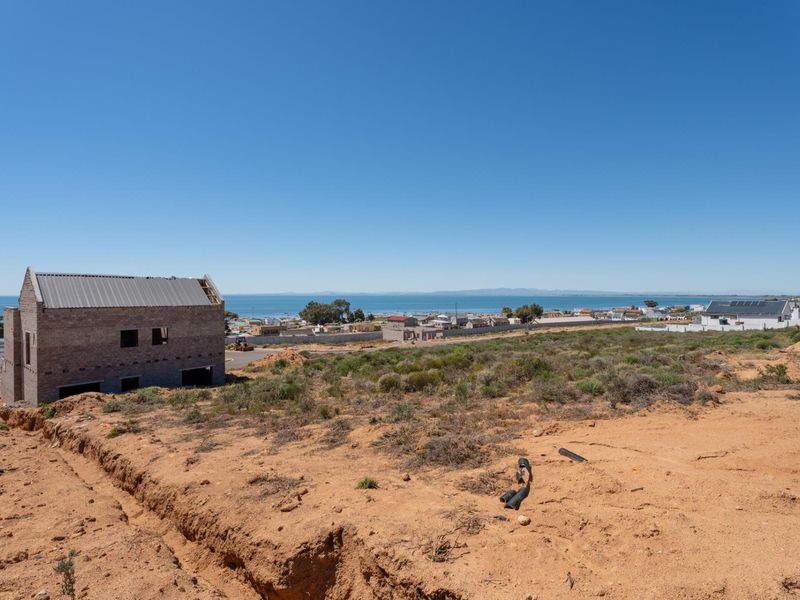 A vacant residential plot featuring a coastal view and a partially constructed building structure, offering significant potential for development.