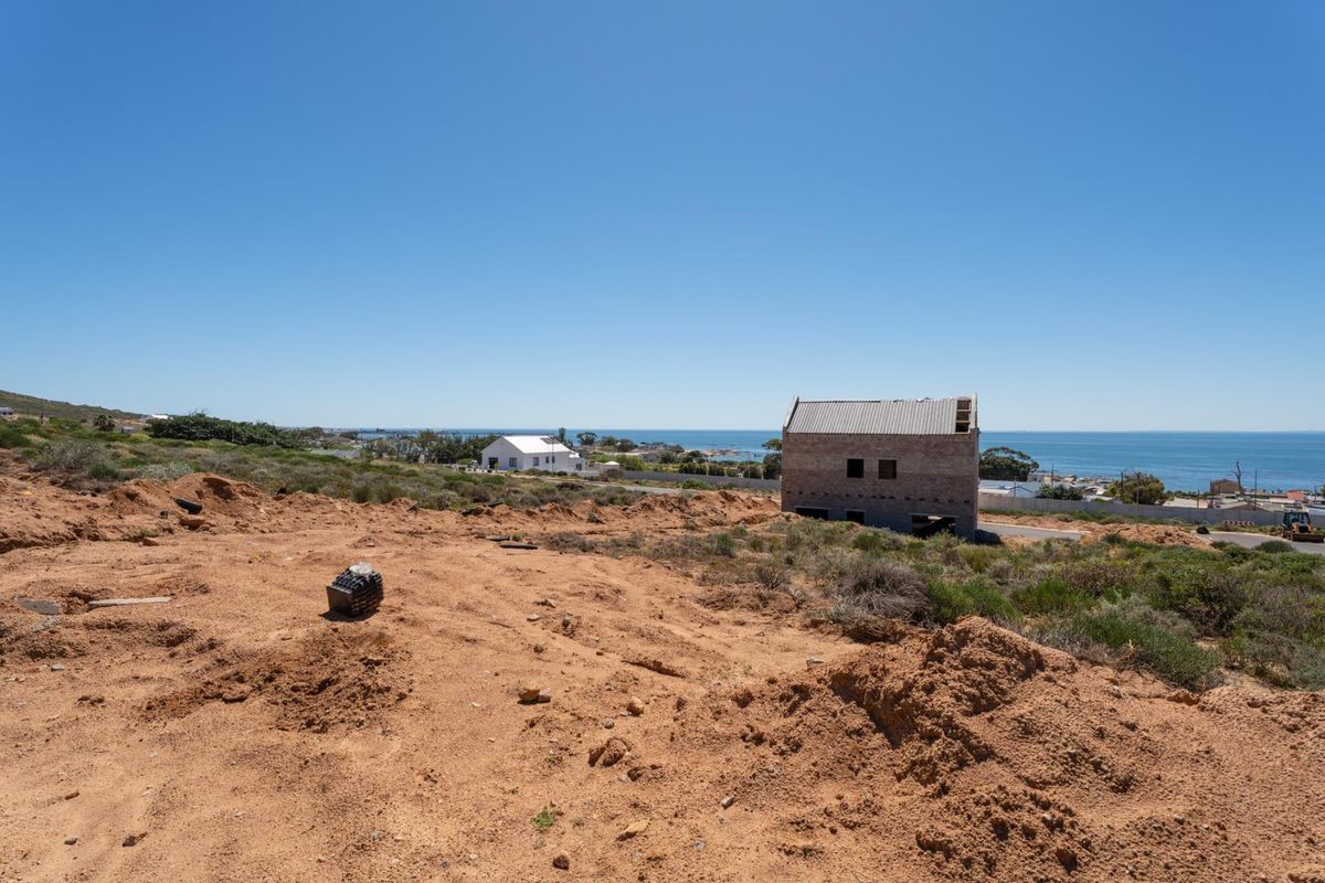 A vacant residential plot featuring an unfinished building structure with scenic coastal views and natural terrain.