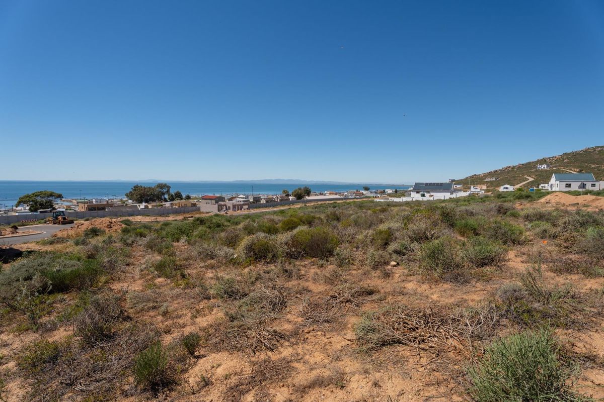 A wide-angle view of the vacant residential land featuring natural coastal vegetation and a clear outlook towards the ocean and surrounding neighborhood.