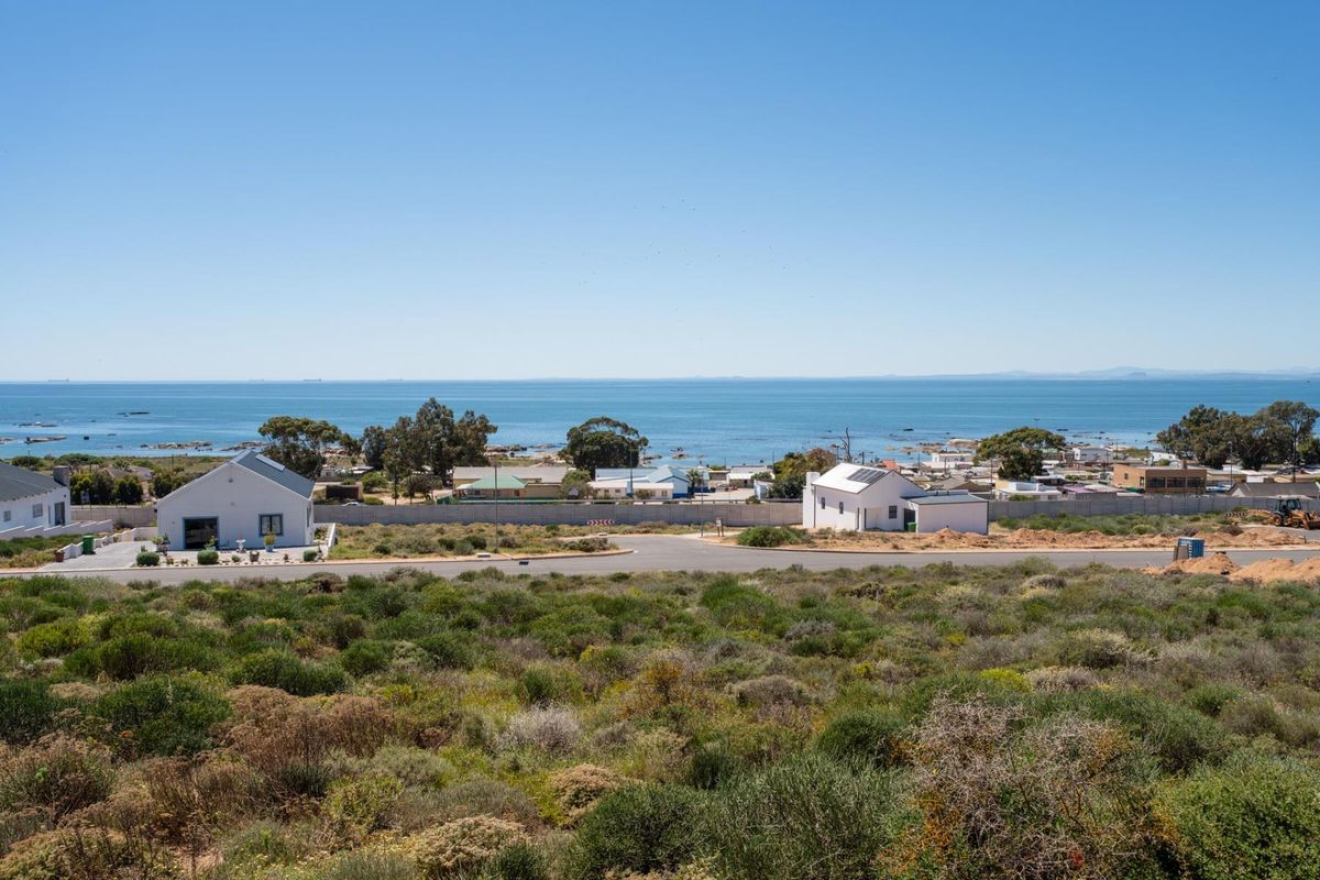 A scenic elevated view overlooking the coastal landscape, nearby residential properties, and the ocean horizon.