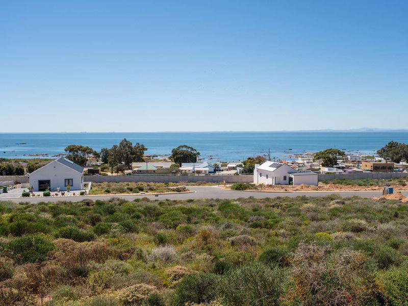 A scenic elevated view overlooking the coastal landscape, nearby residential properties, and the ocean horizon.