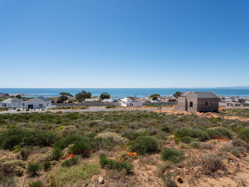 A wide-angle view of the coastal landscape and ocean, showcasing the surrounding neighborhood and natural terrain.