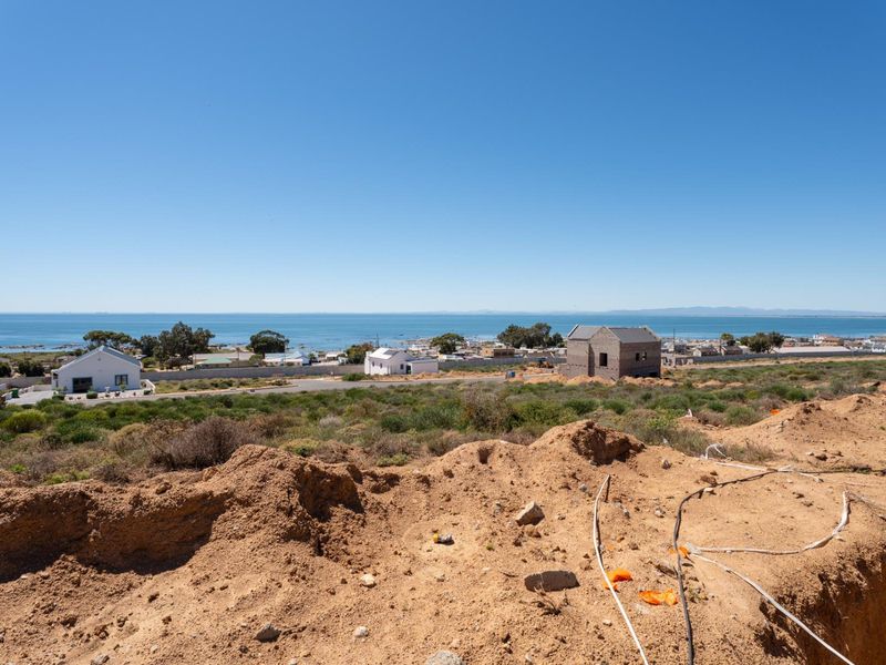A wide-angle view of the coastal landscape and ocean from the vacant residential plot, showcasing the surrounding neighborhood and horizon.