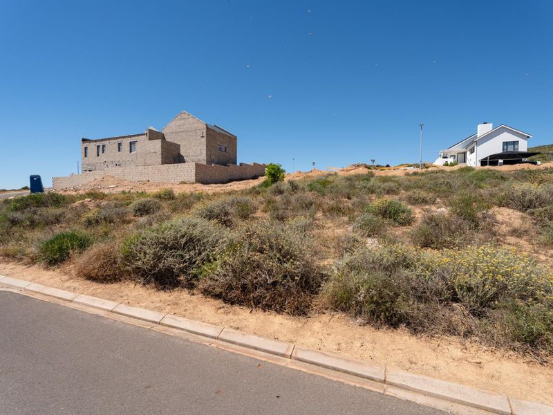 Vacant residential land featuring an unfinished concrete block structure and natural vegetation, situated in a developing neighborhood.