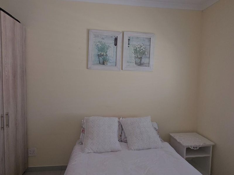 A tidy bedroom featuring a built-in wardrobe, neutral wall finishes, and venetian blinds allowing natural light.
