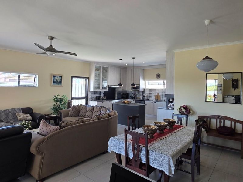 Spacious open-plan living, dining, and kitchen area featuring tiled floors, a central kitchen island, and neutral wall finishes.
