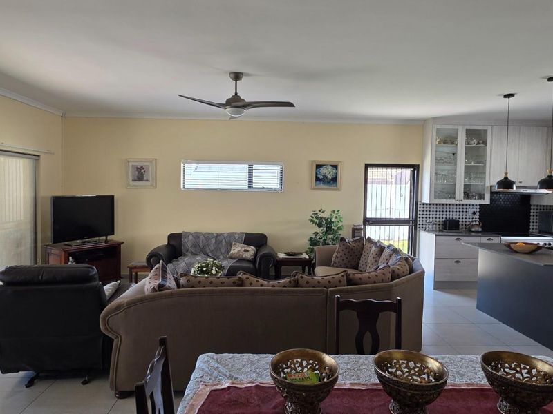 Spacious open-plan living, dining, and kitchen area featuring tiled floors, modern cabinetry, a central island, and direct access to an outdoor patio.