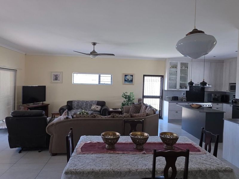 Spacious open-plan living, dining, and kitchen area featuring tiled floors, modern cabinetry, and direct access to the outdoor space through sliding doors.