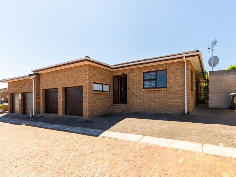 Front exterior view of a face brick house featuring a double garage, paved driveway, and secure entrance.