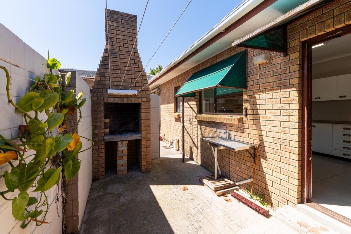 Rear exterior area featuring a brick built-in braai, concrete patio, and an external utility sink, providing a functional outdoor space.