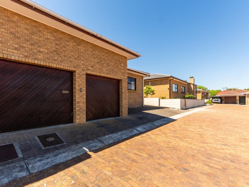 A view of the front exterior featuring a double garage with timber doors and a paved driveway in a residential setting.