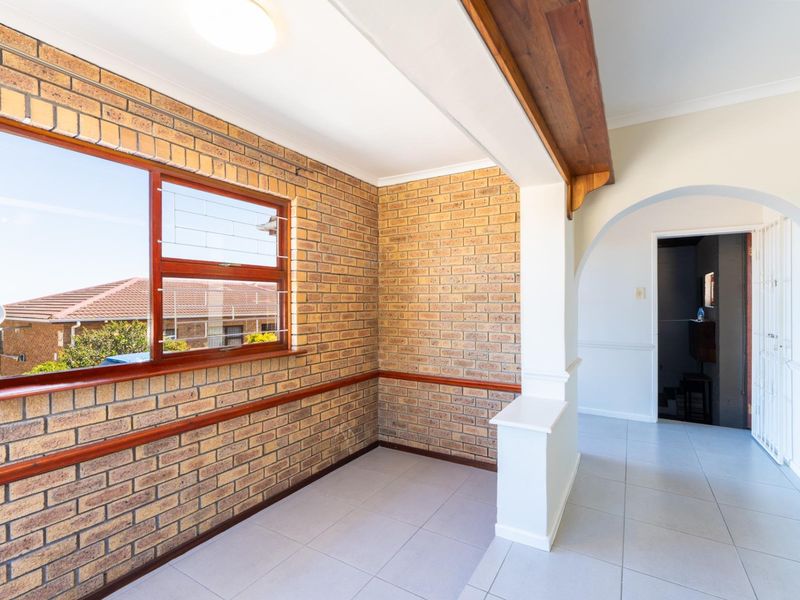 Bright living area featuring exposed brick walls, ceramic floor tiles, and an elegant archway leading to an adjacent space.