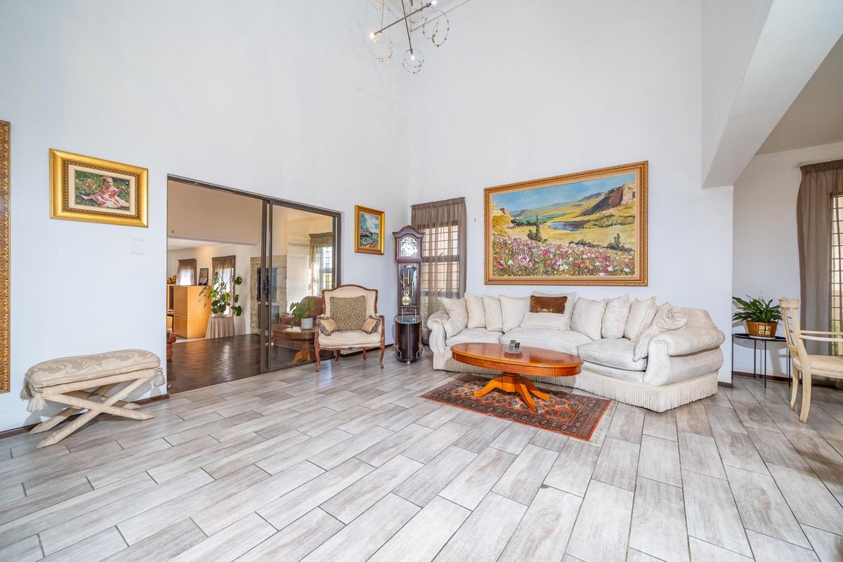 Spacious living room featuring high vaulted ceilings, modern wood-look tile flooring, and large sliding glass doors leading to an adjacent room.