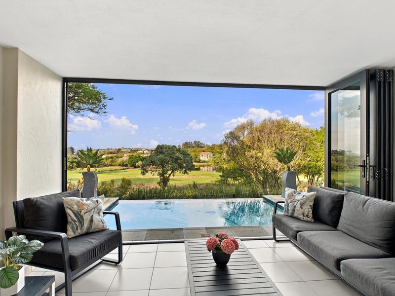 Covered patio featuring modern stacking glass doors opening directly onto a private plunge pool with scenic golf course views.