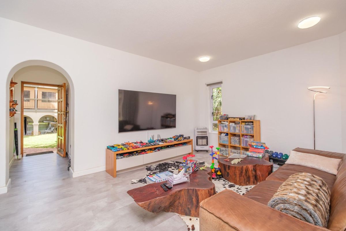 A bright living room featuring an arched entryway, modern laminate flooring, and recessed lighting, providing a clean and functional space.