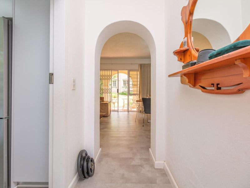 A bright hallway featuring an elegant arched doorway leading into the main living area, finished with neutral floor tiles.