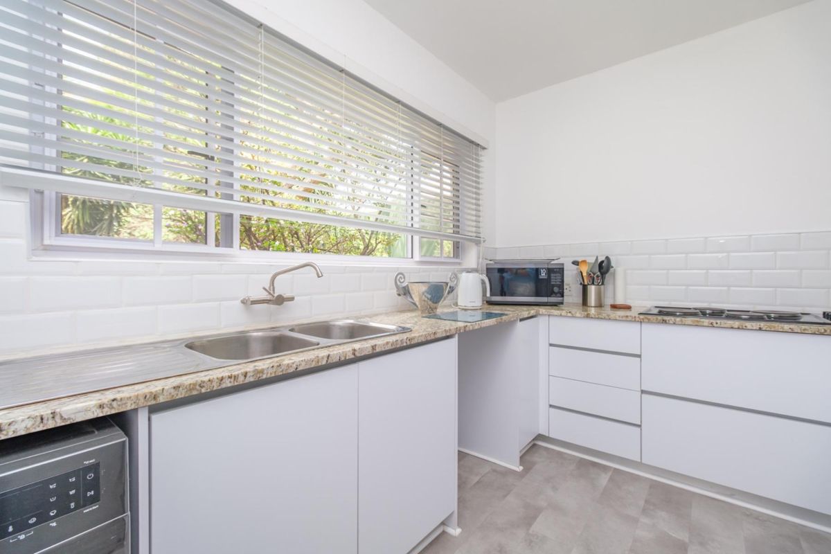 A clean, functional kitchen featuring white cabinetry, granite countertops, a double stainless steel sink, and a classic subway tile backsplash.