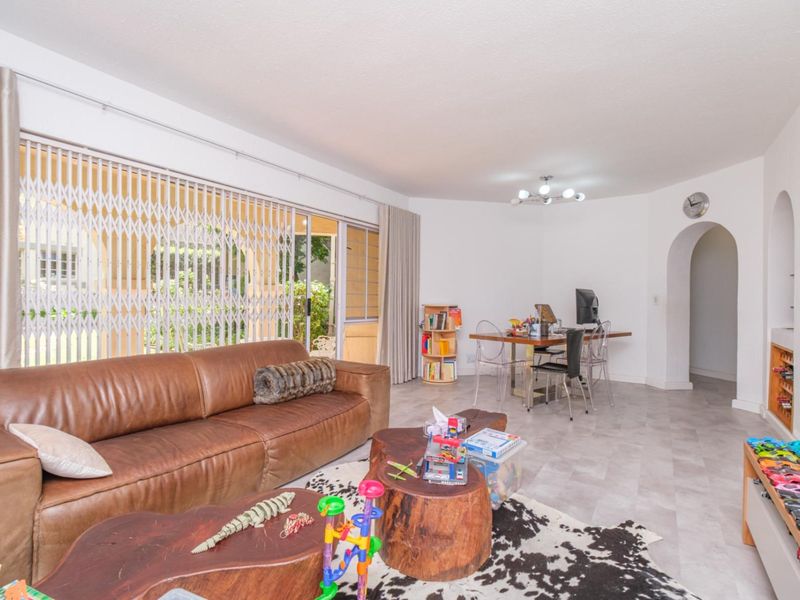 Spacious open-plan living and dining area featuring tiled flooring, an elegant archway, and large sliding glass doors leading to an outdoor space.